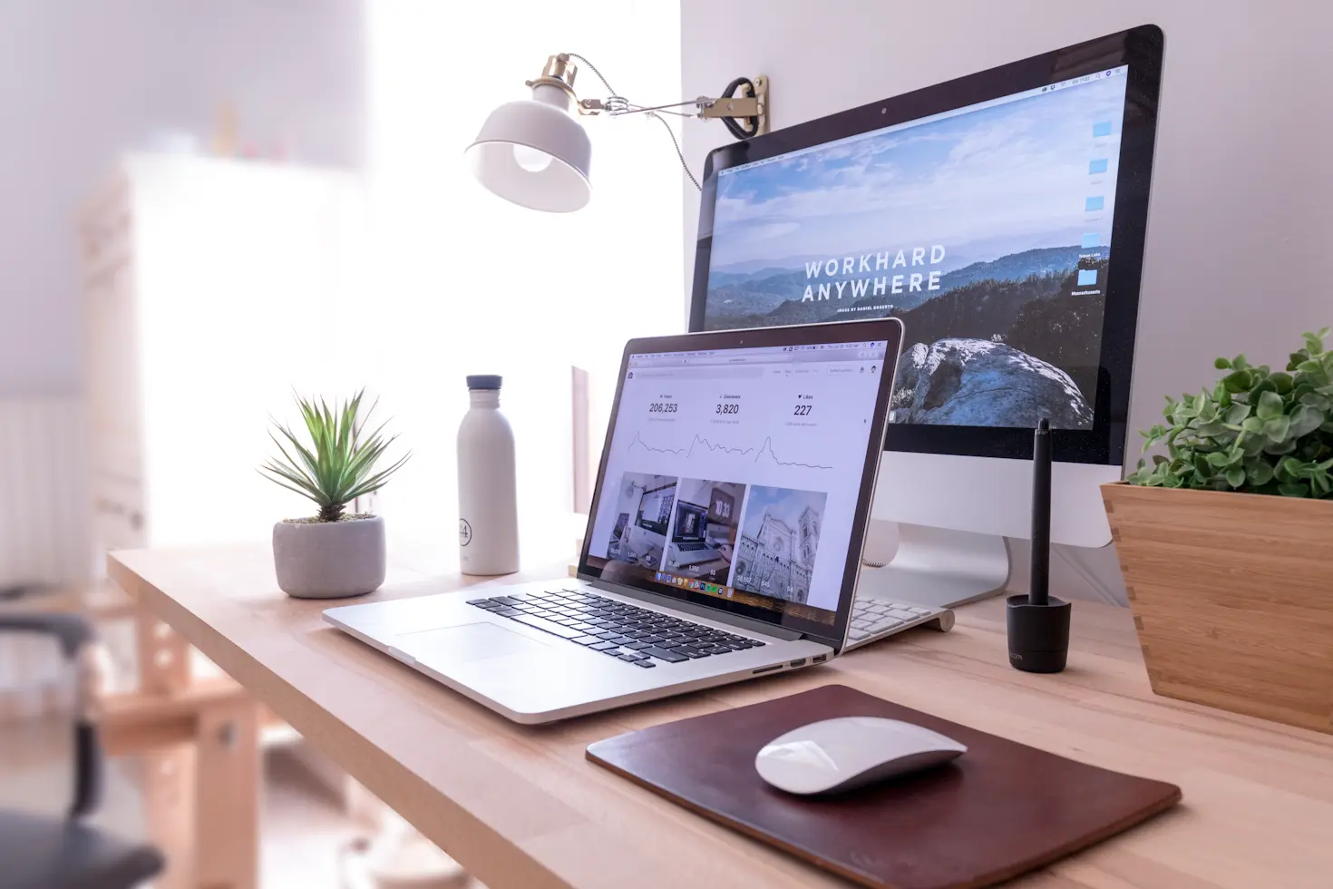 Modern workspace with laptop and desktop showing web development and analytics